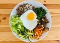 A topdown view of a plate of vegetables, chopped meat, and an egg on top.