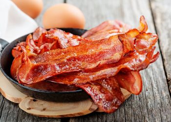 Closeup of bacon in a pan on a table.