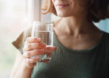 A woman holding a glass of water.