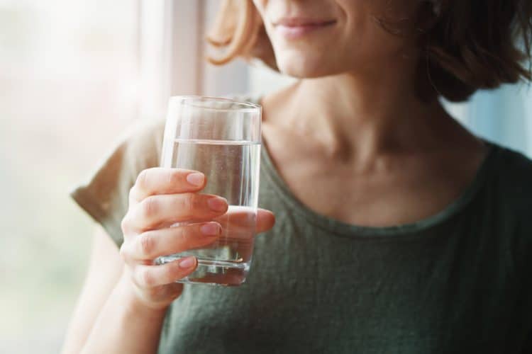 A woman holding a glass of water.