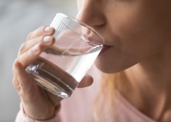 A closeup of a woman drinking some water from a glass.