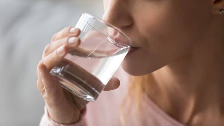 A closeup of a woman drinking some water from a glass.