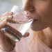 A closeup of a woman drinking some water from a glass.