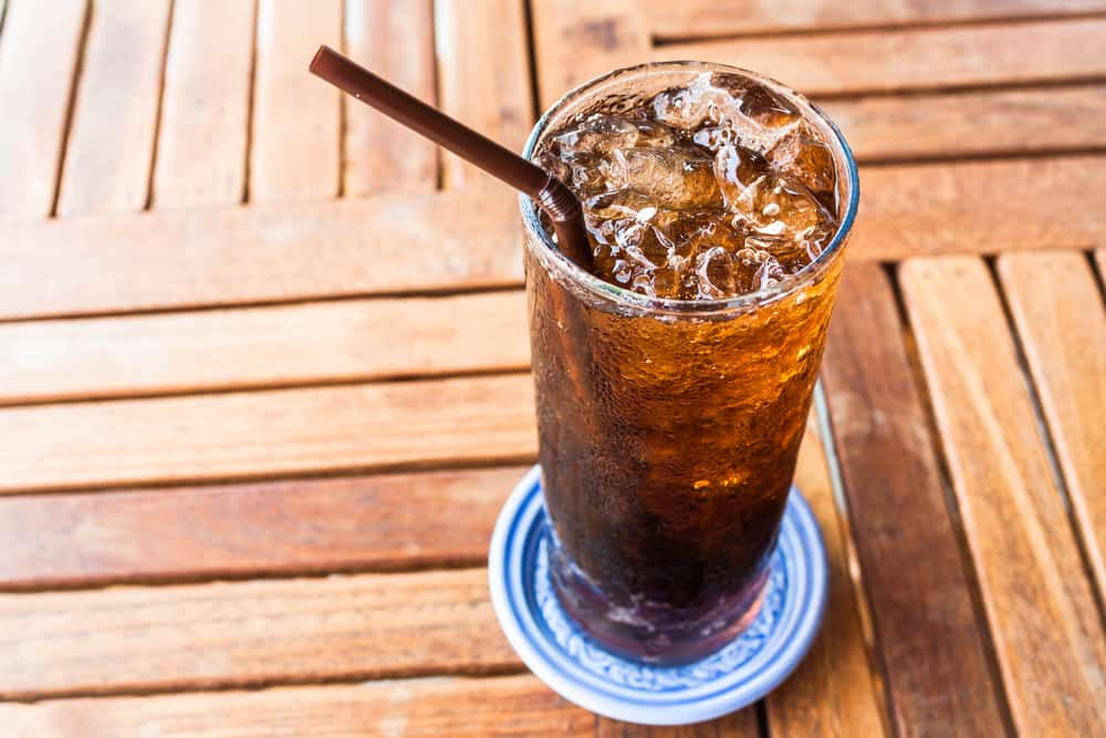 A closeup of a glass of soda with a straw in it.