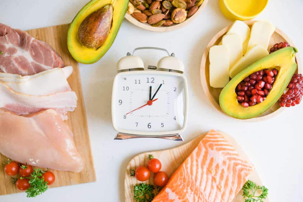 A closeup of a timer clock surrounded by various healthy food items.