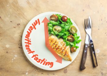 A closeup overhead shot of a plate with food on it arranged like a clock and utensils nearby.