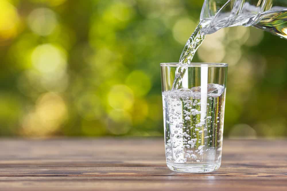 Some water being poured into a glass outside.