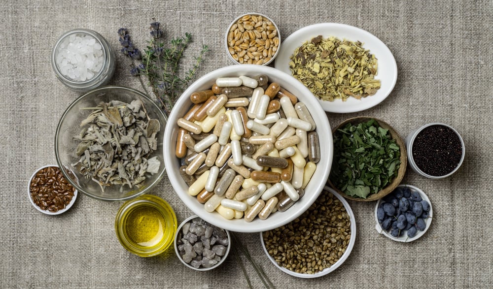 Top-down image of a bowl of supplements and some natural things that go in them.