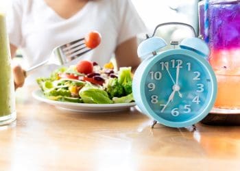 An image showing a clock and someone eating a salad.