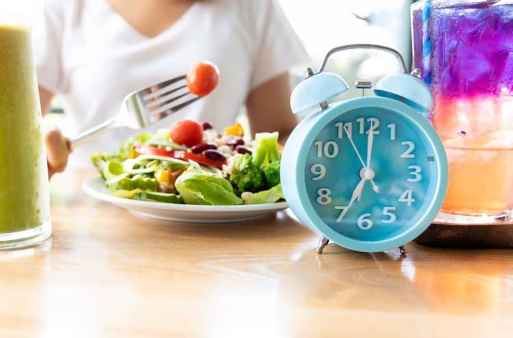 An image showing a clock and someone eating a salad.