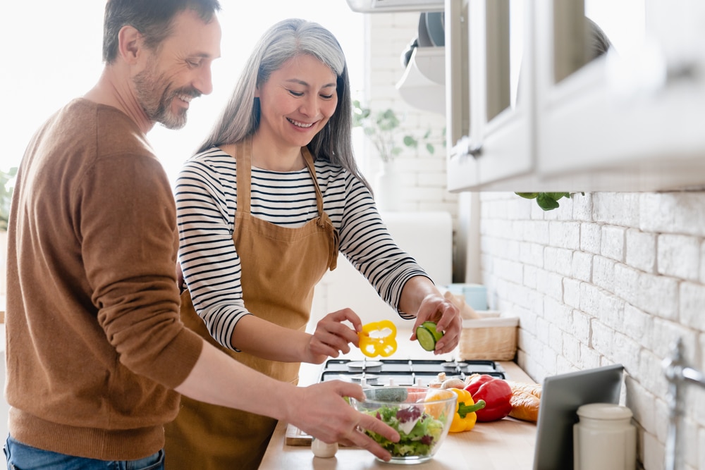 A couple making a salad in their kitchen.