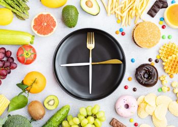 A plate and utensils arranged like a clock with food items surrounding them.
