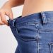 A closeup of a thin woman pulling the waistline of her jeans out to show how thin she is.