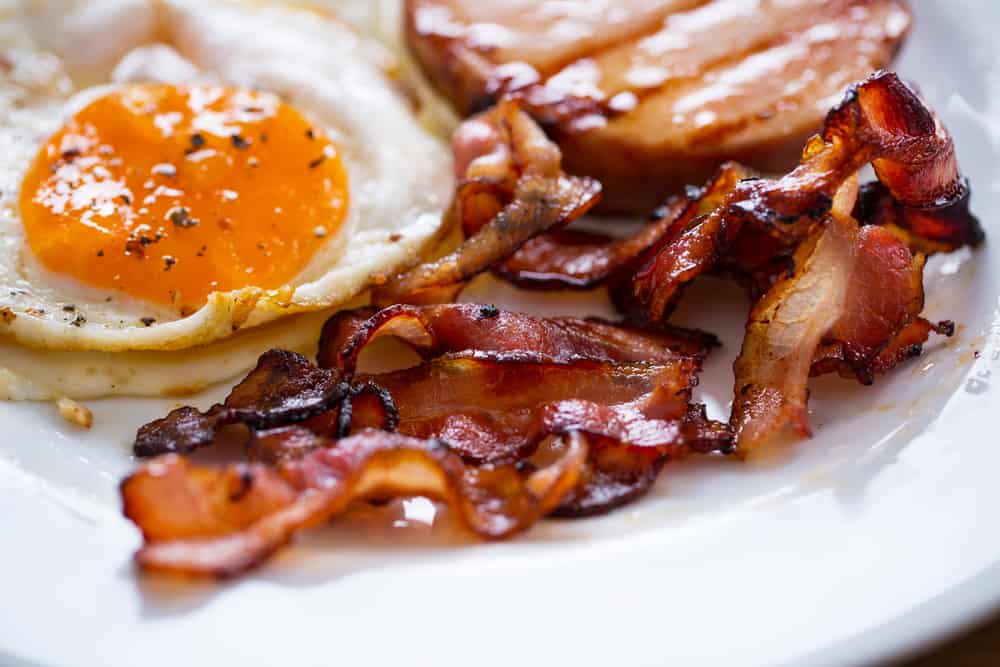 Closeup of a plate showing eggs and bacon.