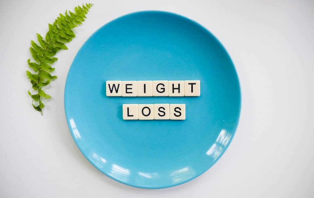 A topdown view of a blue plate with the words "Weight loss" on it, spelled with game tiles.